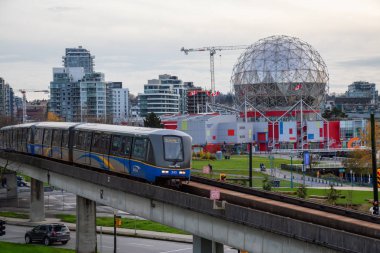 Downtown Vancouver, British Columbia, Canada - November 29, 2018: Skytrain passing in the modern city during a cloudy evening. clipart