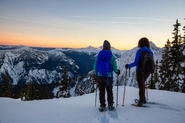 Freunde Des Ehepaares Gehen Bei Einem Lebendigen Wintersonnenuntergang Schneeschuhwandern Auf — Stockfoto