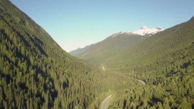 Güneşli bir yaz sabahı Güzel Kanada Dağları ile çevrili doğal bir yolun havadan görünümü. Revelstoke, British Columbia, Kanada yakınlarında çekilmiş.