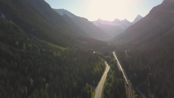 在阳光明媚的夏日 在风景优美的公路上 有火车的鸟瞰图 周围环绕着美丽的加拿大山脉 在加拿大不列颠哥伦比亚省雷维尔斯托克附近拍摄 — 图库视频影像