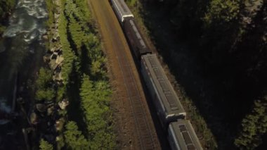 Güneşli bir yaz günü boyunca Güzel Kanada Dağları ile çevrili doğal bir yol yakınında bir trenhavadan görünümü. Revelstoke, British Columbia, Kanada yakınlarında çekilmiş.