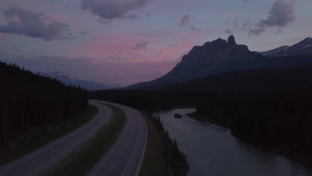 カラフルな夏の日の出の間に美しいカナダの山の風景に囲まれた谷の風光明媚な道路の航空写真 カナダ アルバータ州バンフ付近で撮影 — ストック動画