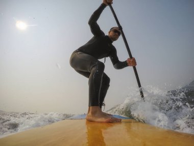 Adam kürek sörfçü bir dalga Pasifik Okyanusu biniyor. Estevan, Vancouver Adası, British Columbia, Kanada alınan.
