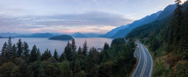Aerial panoramic view of the scenic highway surounded by the Beautiful Canadian Mountain Landscape during a summer sunrise. Taken in Sunset Beach, North of Vancouver, British Columbia, Canada. clipart