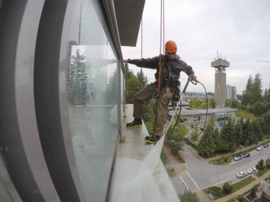 Burnaby, Vancouver, Bc, Kanada - 07 Temmuz 2018: Yüksek artış ip teknisyen hangining bina ve güç bir bulutlu gün boyunca yıkama tarafında olan.