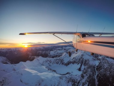 Rocky Candian Dağları yakınında canlı bir gün batımı sırasında uçan küçük uçak. Vancouver, British Columbia, Kanada kuzeyindeki alınan.