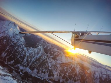 Rocky Candian Dağları yakınında canlı bir gün batımı sırasında uçan küçük uçak. Vancouver, British Columbia, Kanada kuzeyindeki alınan.