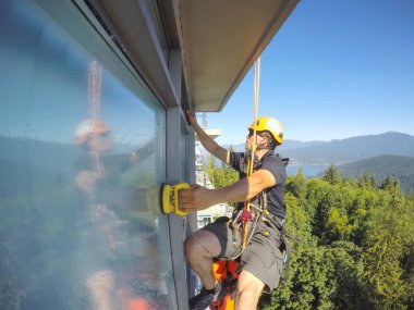 Burnaby, Vancouver, Bc, Kanada - 08 Temmuz 2018: Yüksek artış ip teknisyen hangining inşaat ve temizlik windows tarafında olan.