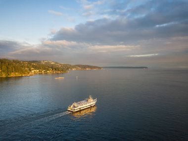 Aerial view of a ferry boat in the ocean during a vibrant cloudy sunset. Taken in Horseshoe Bay, West Vancouver, British Columbia, Canada. clipart