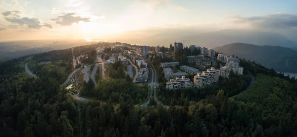 Aerial view of residential buildings on top of Burnaby Mountain during a vibrant sunset. Taken in Greater Vancouver, BC, Canada.