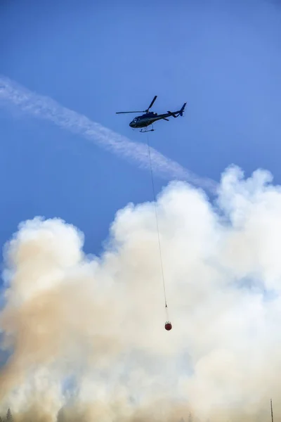 Helicopter fighting BC forest fires during a hot sunny summer day. Taken near Port Alice, Northern Vancouver Island, British Columbia, Canada.