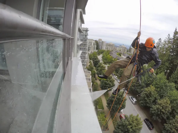 Burnaby, Vancouver, Bc, Kanada - 07 Temmuz 2018: Yüksek artış ip teknisyen hangining bina ve güç bir bulutlu gün boyunca yıkama tarafında olan.