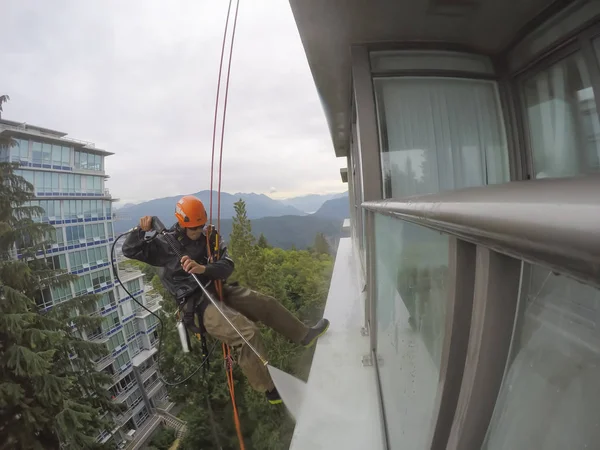 Burnaby, Vancouver, Bc, Kanada - 07 Temmuz 2018: Yüksek artış ip teknisyen hangining bina ve güç bir bulutlu gün boyunca yıkama tarafında olan.