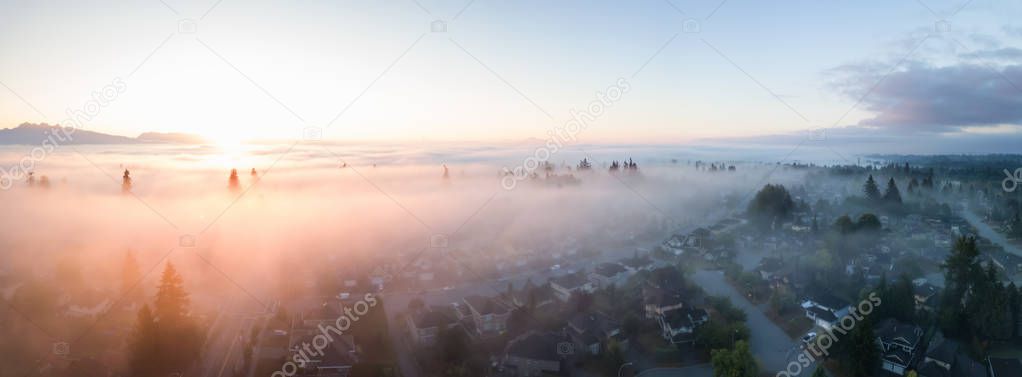 Aerial view of a residential neighborhood covered in a layer of fog during a vibrant sunrise. Taken in Greater Vancouver, BC, Canada.