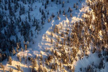 Güneşli bir kış gün batımı sırasında karla kaplı dağ sırası yukarıdan havadan görünümü. Vancouver'ın kuzeyi alındı, British Columbia, Kanada.