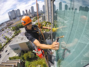 Burnaby, Vancouver, British Columbia, Kanada - 2 Temmuz 2018: Yüksek katlı halat erişim pencere temizleyicisi bir yaz günü çalışıyor.