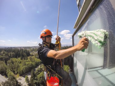 Burnaby, Vancouver, British Columbia, Kanada - 07 Temmuz 2018: Yüksek katlı halat erişim pencere temizleyici sıcak güneşli bir yaz günü boyunca çalışıyor.