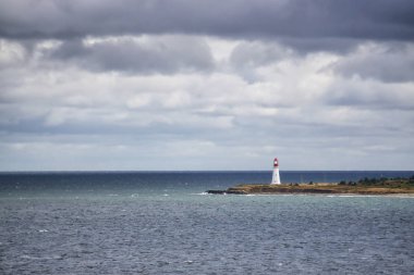 Bulutlu bir günde okyanus kıyısında ki deniz feneri. New Victoria, Nova Scotia, Kanada'da çekildi.