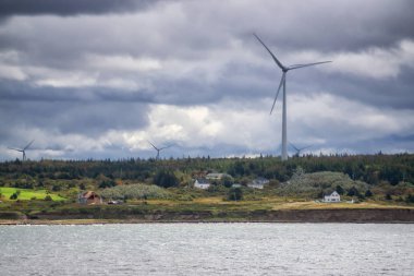 Bulutlu bir günde okyanus kıyısında rüzgar türbini. New Victoria, Nova Scotia, Kanada 'da çekildi.