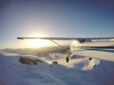Canlı bir yaz gün batımı sırasında kayalık Kanada Dağları yakınında uçan küçük bir uçak. Squamish yakınlarında çekilmiş, Vancouver'ın kuzeyi, British Columbia, Kanada.