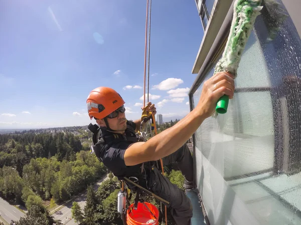 Burnaby, Vancouver, British Columbia, Kanada - 2 Temmuz 2018: Yüksek katlı halat erişim pencere temizleyicisi bir yaz günü çalışıyor.