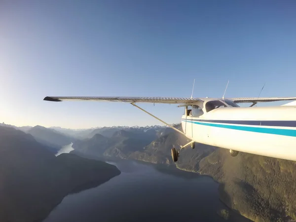 在充满活力的夏日日落期间 小型飞机在岩石的加拿大山脉附近飞行 位于加拿大不列颠哥伦比亚省温哥华以北的斯夸米什附近 — 图库照片