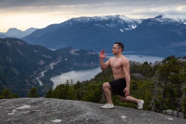 Fit ve Kaslı Genç Adam bulutlu bir gün batımı sırasında Dağın tepesinde egzersizler yapıyor. Squamish'teki Chief Mountain'da alındı, Vancouver'ın kuzeyinde, Bc, Kanada.