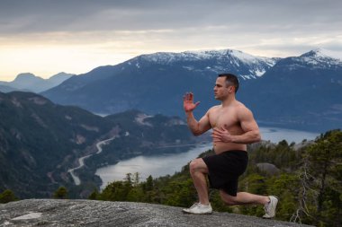 Fit ve Kaslı Genç Adam bulutlu bir gün batımı sırasında Dağın tepesinde egzersizler yapıyor. Squamish'teki Chief Mountain'da alındı, Vancouver'ın kuzeyinde, Bc, Kanada.