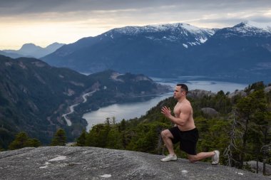 Fit ve Kaslı Genç Adam bulutlu bir gün batımı sırasında Dağın tepesinde egzersizler yapıyor. Squamish'teki Chief Mountain'da alındı, Vancouver'ın kuzeyinde, Bc, Kanada.