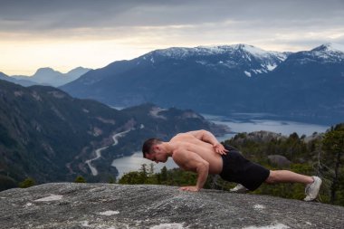 Fit ve Kaslı Genç Adam bulutlu bir gün batımı sırasında Dağın tepesinde egzersizler yapıyor. Squamish'teki Chief Mountain'da alındı, Vancouver'ın kuzeyinde, Bc, Kanada.