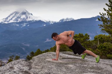 Fit ve Kaslı Genç Adam bulutlu bir gün boyunca Dağın tepesinde egzersizler yapıyor. Squamish'teki Chief Mountain'da alındı, Vancouver'ın kuzeyinde, Bc, Kanada.