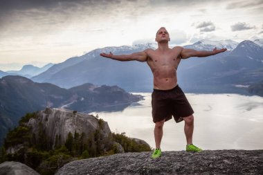 Fit ve Kaslı Genç Adam bulutlu bir gün boyunca Dağın tepesinde. Squamish'teki Chief Mountain'da alındı, Vancouver'ın kuzeyinde, Bc, Kanada.