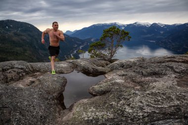 Fit ve Kaslı Genç Adam bulutlu bir gün boyunca Dağ kadar çalışıyor. Squamish'teki Chief Mountain'da alındı, Vancouver'ın kuzeyinde, Bc, Kanada.