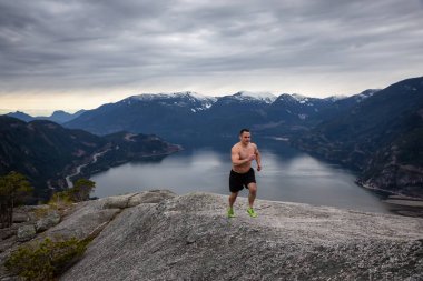 Fit ve Kaslı Genç Adam bulutlu bir gün boyunca Dağ kadar çalışıyor. Squamish'teki Chief Mountain'da alındı, Vancouver'ın kuzeyinde, Bc, Kanada.