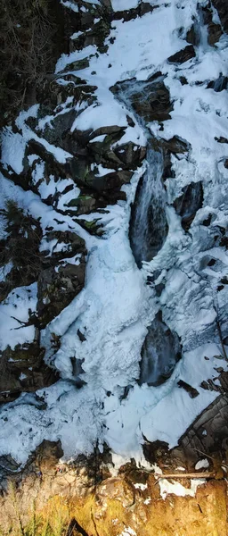 Beautiful aerial panoramic view of a waterfall, Crooked Falls, covered in melting ice during springtime. Taken near Squamish, North of Vancouver, BC, Canada.