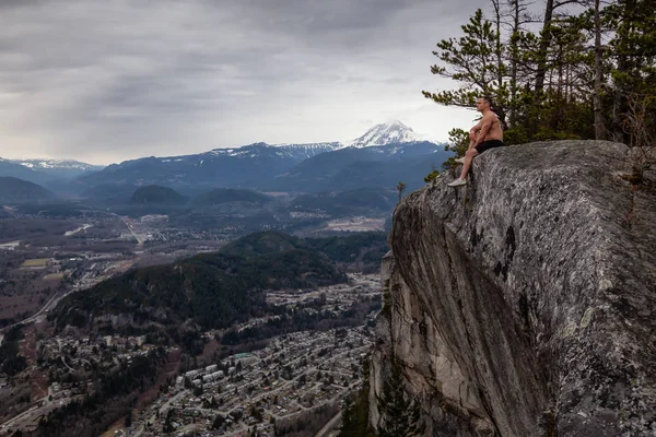 身材健扬的白种人坐在山顶的悬崖上 享受着风景 拍摄于加拿大不列颠哥伦比亚省温哥华以北的斯夸米什 — 图库照片