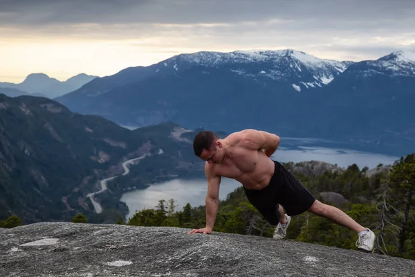 健身和肌肉的年轻人在多云的日落期间在山顶上做运动 拍摄于加拿大不列颠哥伦比亚省温哥华以北的斯夸米什头山 — 图库照片