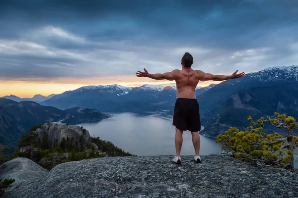 フィットと筋肉の若者は カラフルな夕日の間に山の上にあります カナダ バンクーバー北部 スカーミッシュのチーフマウンテンで撮影 — ストック写真