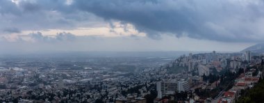 Bulutlu bir gün batımı sırasında Akdeniz kıyısında bir şehrin güzel panoramik görünümü. Hayfa, İsrail'de çekilmiş.