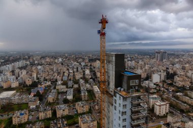 Netanya, Center District, Israel - 31 Mart 2019: Bulutlu bir gün doğumu sırasında bir şehirdeki bir şantiyenin havadan görünümü.