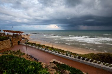 Bulutlu bir gün doğumu sırasında kumlu bir plaj güzel bir görünüm. Alınan Netanya, Center District, İsrail.