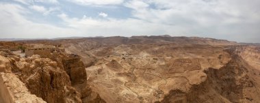 Bulutlu ve güneşli bir günde bir dağın tepesindeki antik bir kalenin güzel panoramik manzarası. Alınan Masada Ulusal Parkı, İsrail.