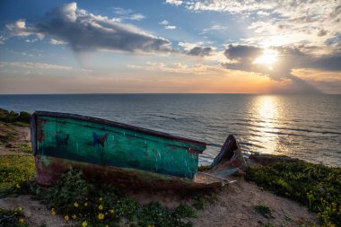 Broken wooden boat on the Ocean Coast duing a vibrant sunset at the Apollonia Beach. Taken in Herzliya, Tel Aviv District, Israel. clipart