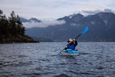 Kayıktaki maceracı adam bulutlu bir akşam da Howe Sound'da kürek çekiyor. Bowen Adası yakınlarında çekilen, Vancouver'ın kuzeybatısında, Bc, Kanada.