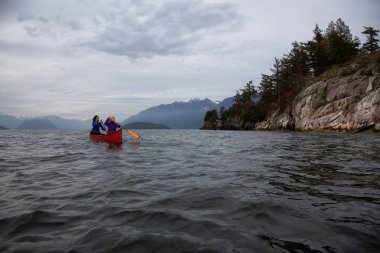 Kırmızı kano üzerinde çift maceracı kadın arkadaşlar bulutlu bir gün batımı sırasında Howe Sound kürek vardır. Horseshoe Bay, Batı Vancouver, Bc, Kanada.