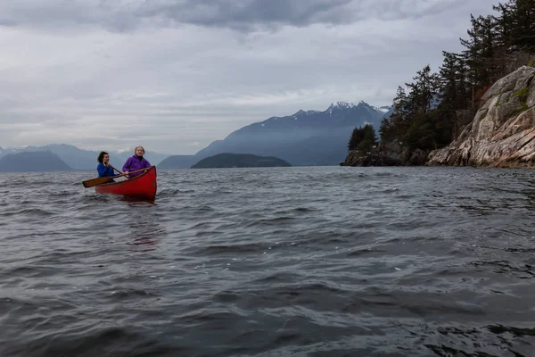 Kırmızı kano üzerinde çift maceracı kadın arkadaşlar bulutlu bir gün batımı sırasında Howe Sound kürek vardır. Horseshoe Bay, Batı Vancouver, Bc, Kanada.