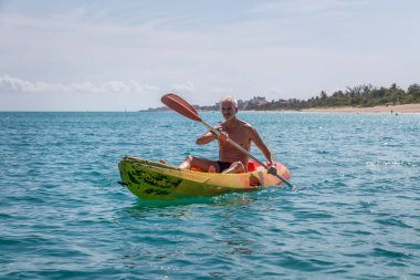 Yaşlı fit adam güneşli bir yaz gününde Karayip Denizi'nde parlak sarı bir kayık üzerinde kayak olduğunu. Varadero, Küba'da çekilmiş.
