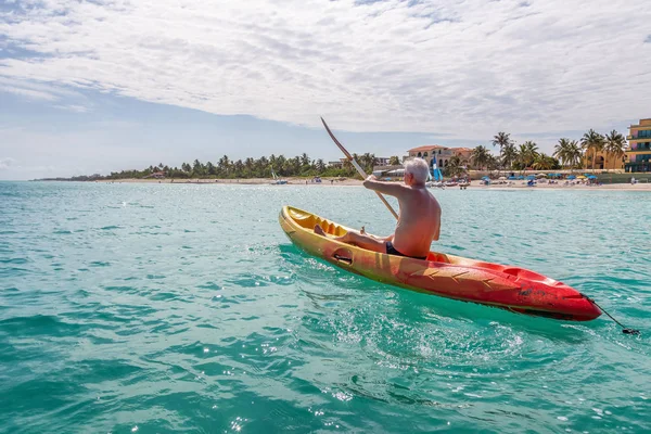 Elder fit man is kayaking on a bright yellow kayak in Caribbean Sea during a sunny summer day. Taken in Varadero, Cuba.