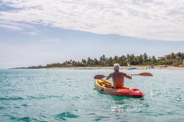 Elder fit man is kayaking on a bright yellow kayak in Caribbean Sea during a sunny summer day. Taken in Varadero, Cuba.