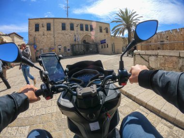 Kudüs, İsrail - 16 Nisan 2019: Bulutlu ve güneşli bir günde yoğun şehir sokaklarında scooter sürmek.